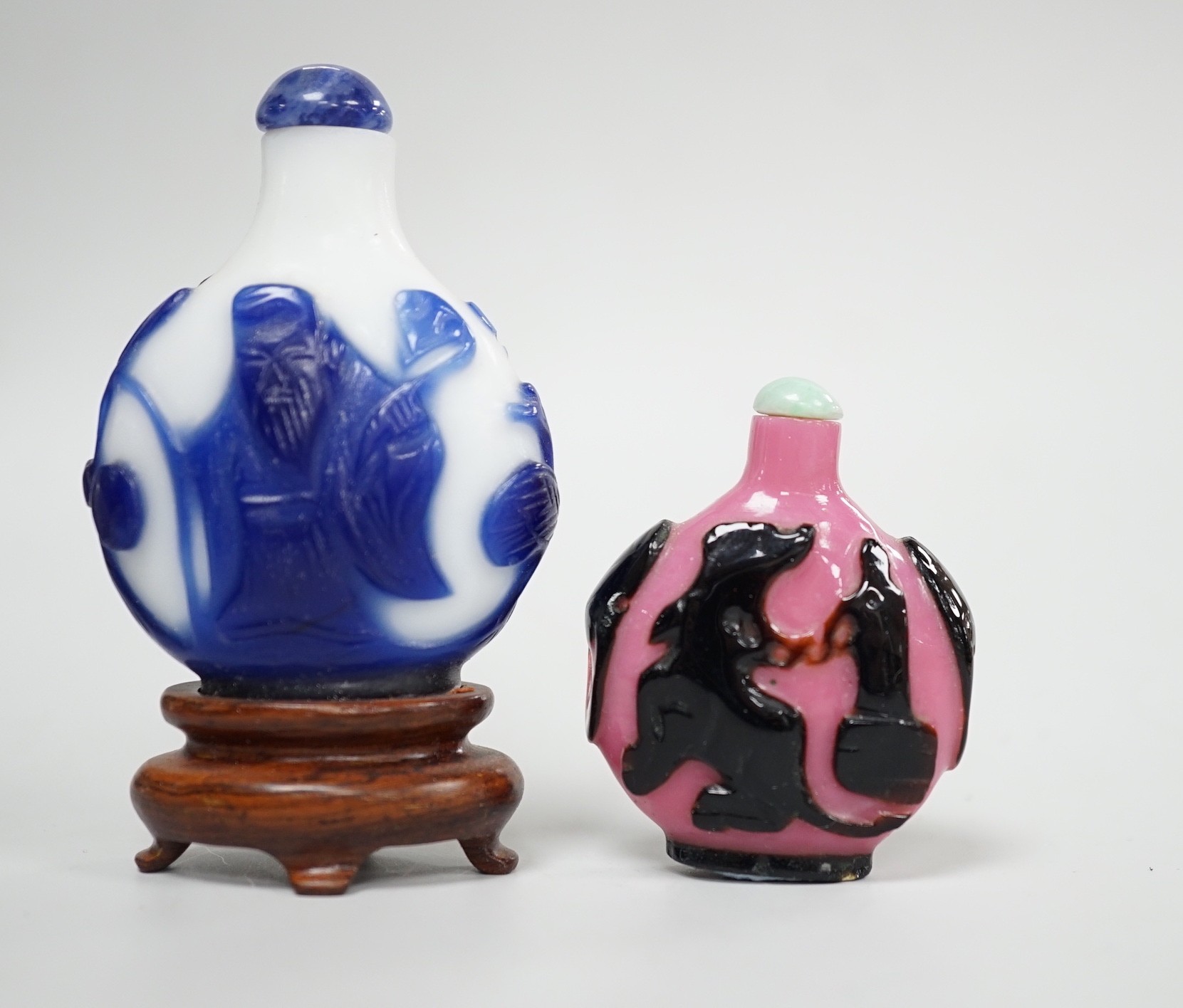 Two Chinese overlay glass snuff bottles, the black and pink bottle in imitation of shadow agate, 18th century, decorated with an eagle and the moon the reverse with a dog tied to a chain, 4.3cm, the blue and white exampl